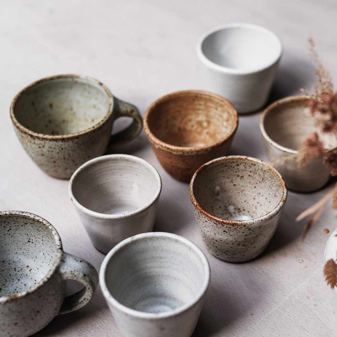 Collection of ceramic cups viewed from above, browns greys and whites in tone.
